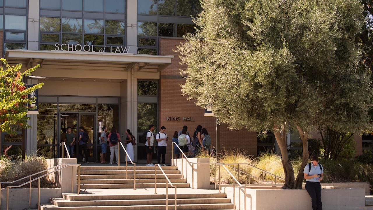 College students stand around outside a school of law building